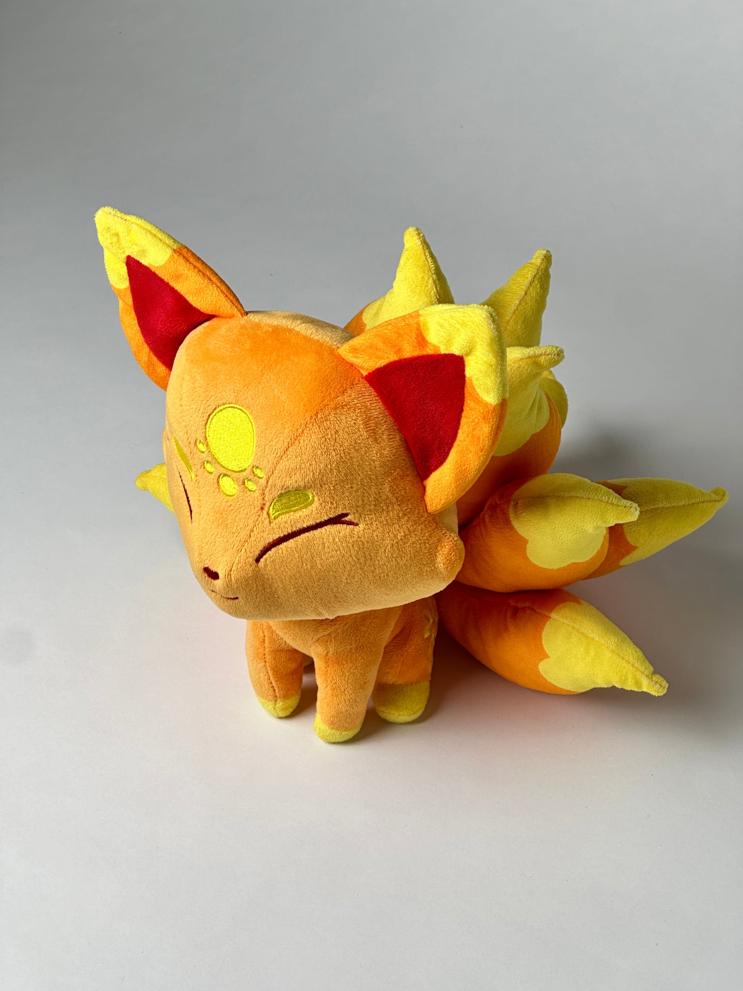 Top view of Cyrus, a orange, yellow, gold kitsune plush.