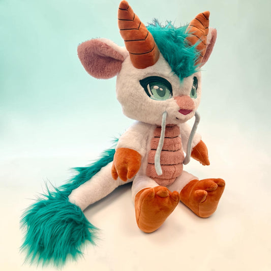 Three-quarter seated view of Huka the Spirited Dragon, a white, orange, teal dragon plush.