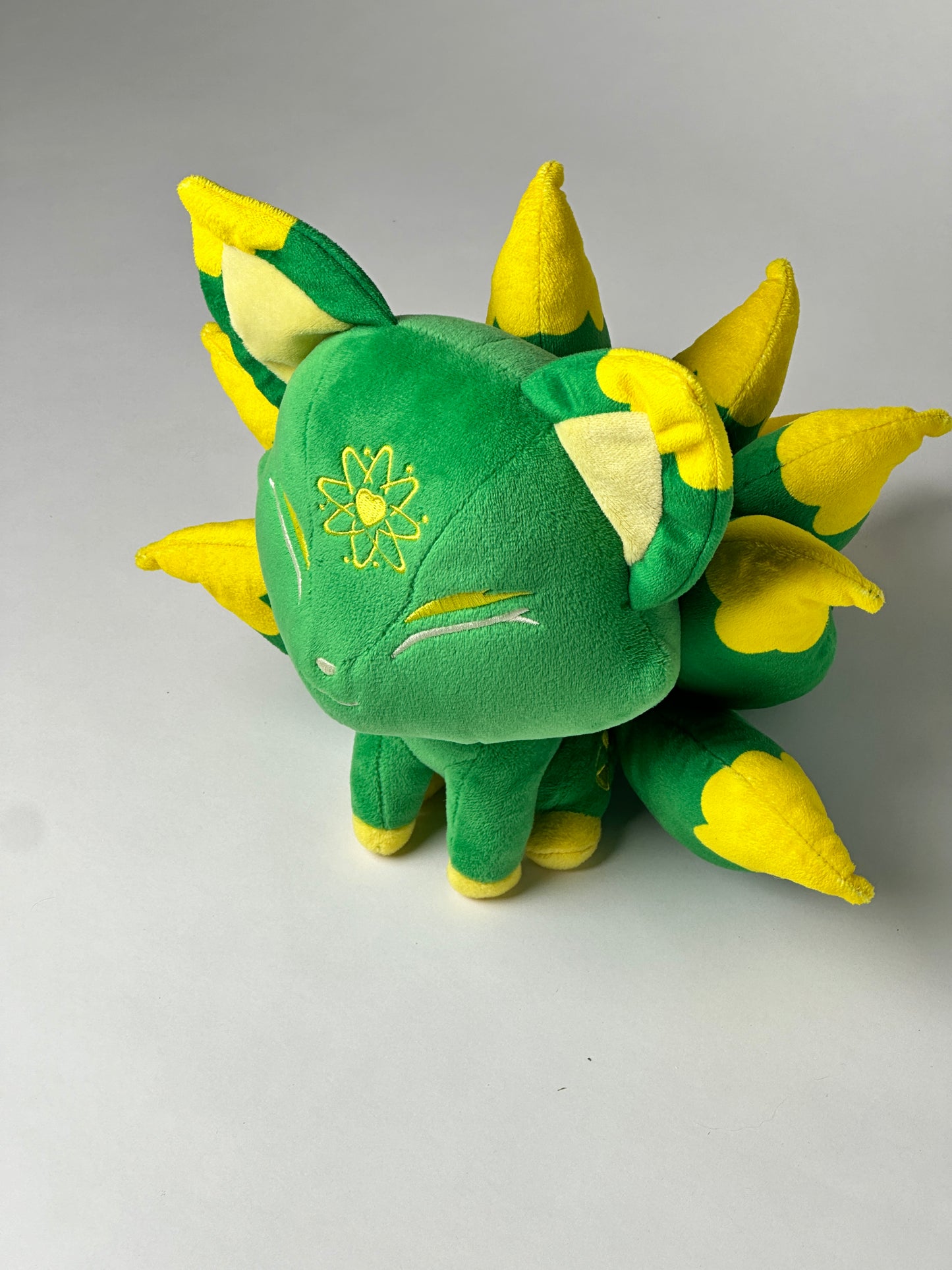 Top view of Radio, a green, yellow, tan kitsune plush.