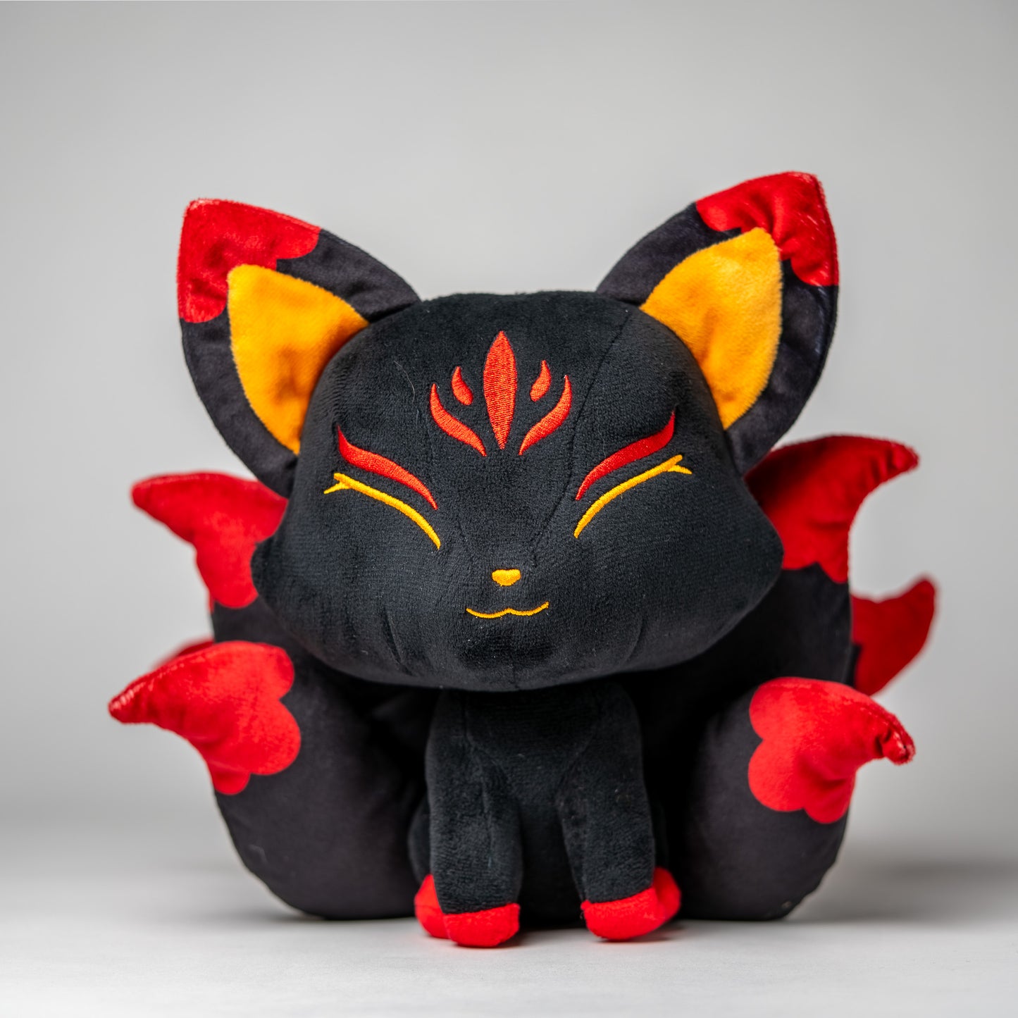 Front view of Baal, a black, red, orange kitsune plush.