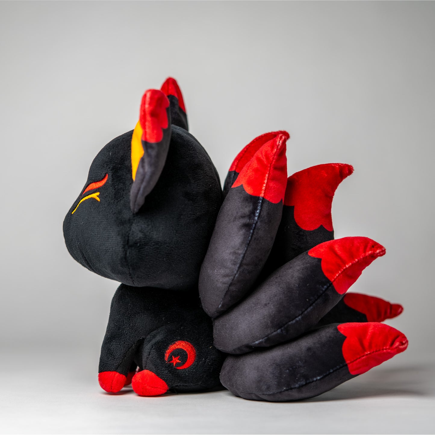 Three-quarter view of Baal, a black, red, orange kitsune plush.