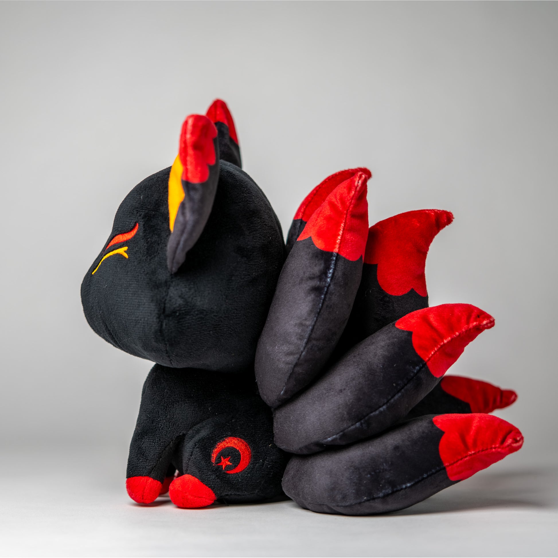 Three-quarter view of Baal, a black, red, orange kitsune plush.