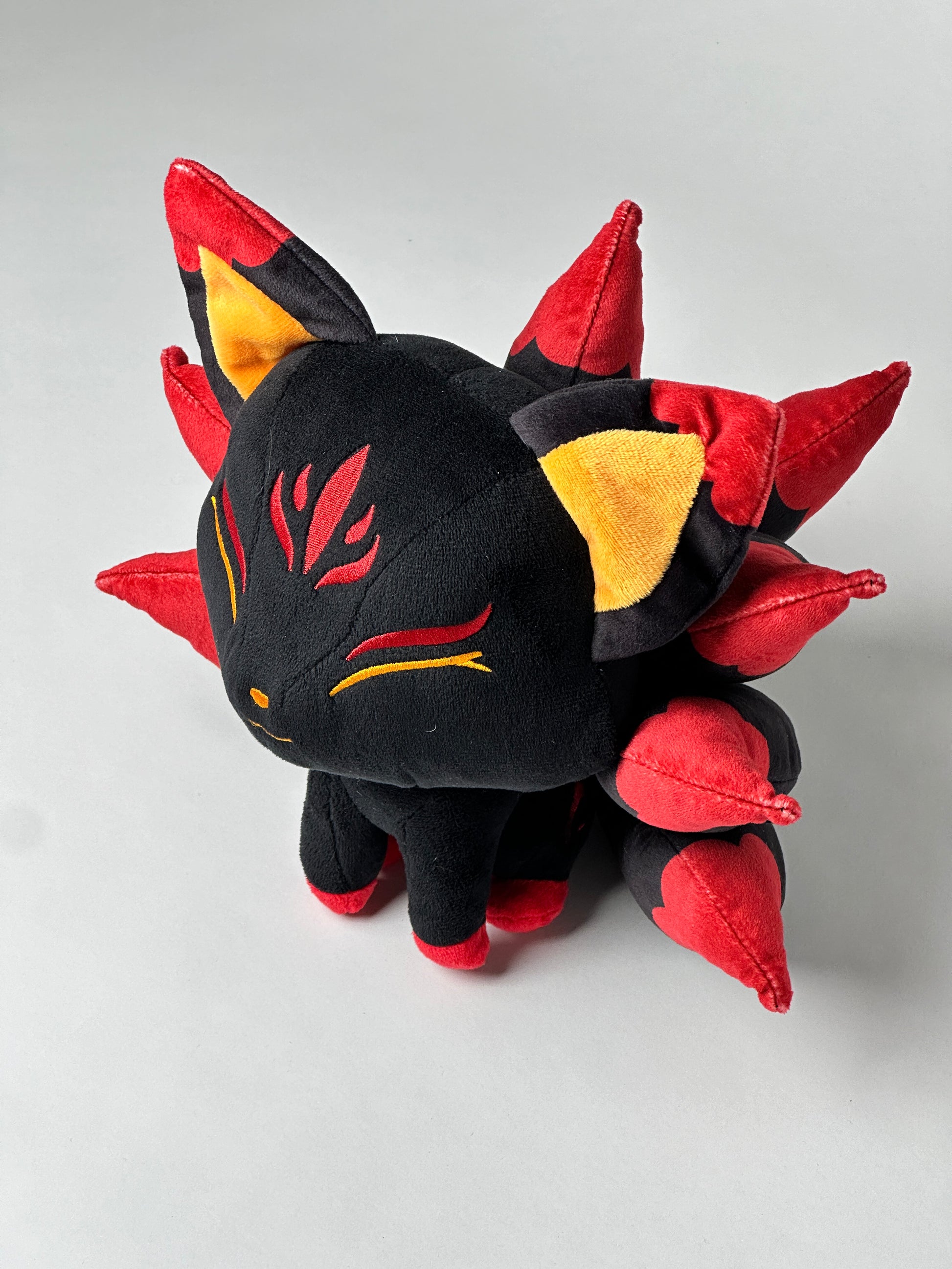 Top view of Baal, a black, red, orange kitsune plush.