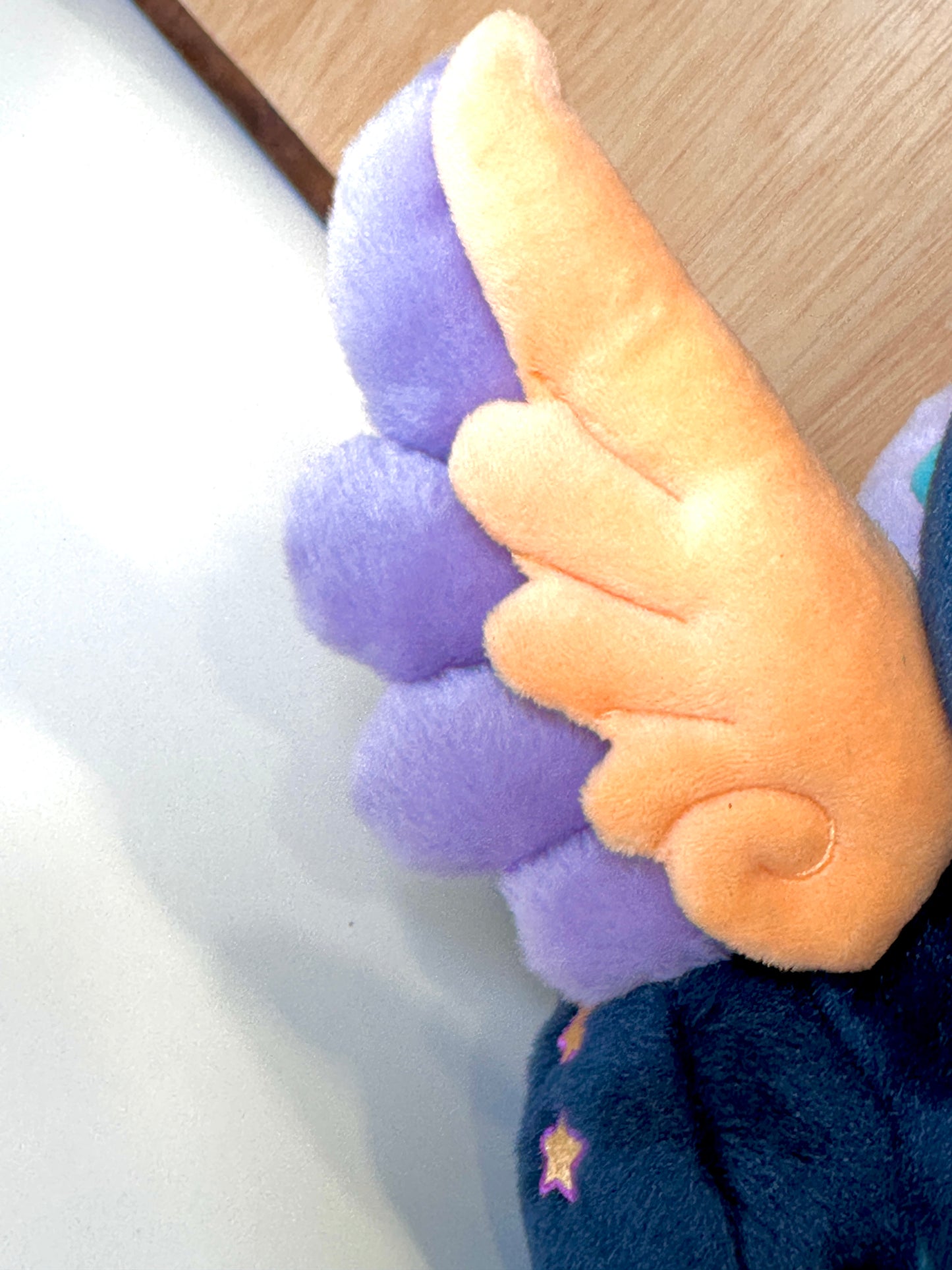 Wing detail of Calypso, a navy, peach, turquoise dragon plush.
