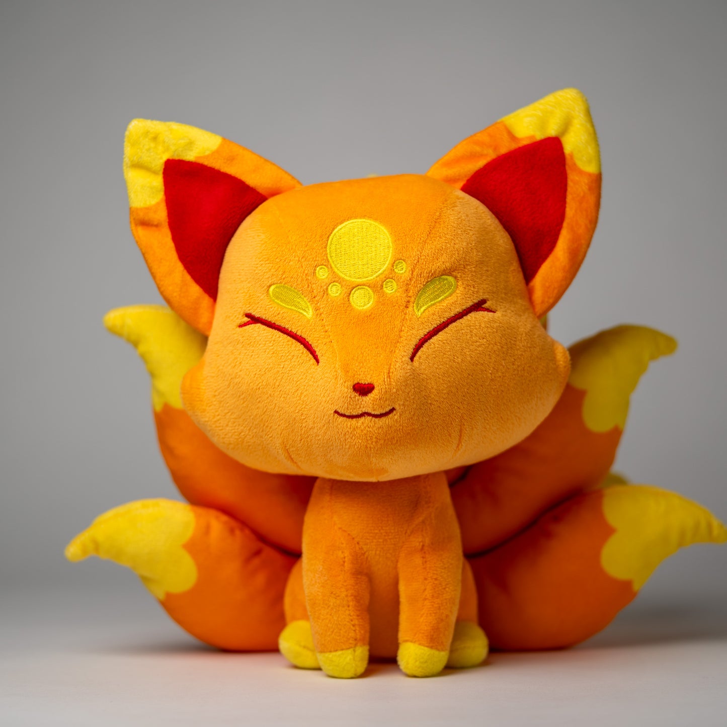 Front view of Cyrus, a orange, yellow, gold kitsune plush.