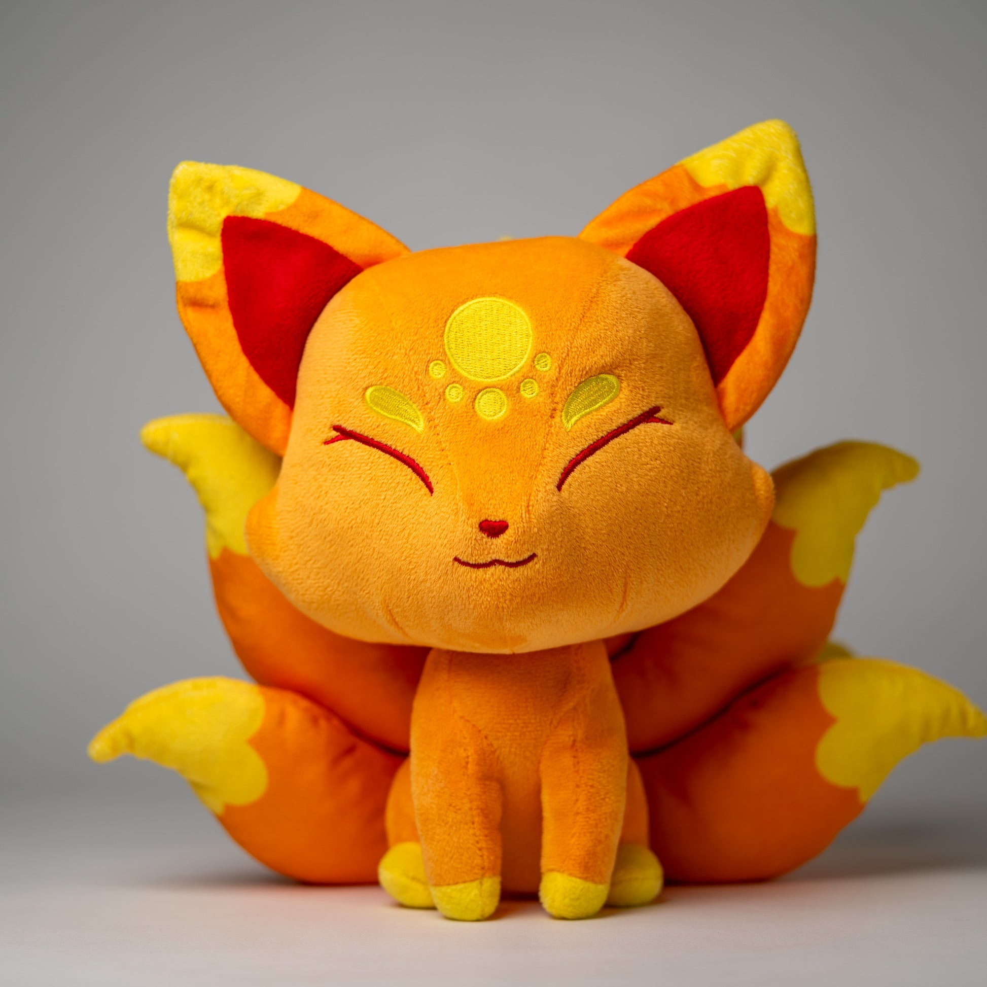 Front view of Cyrus, a orange, yellow, gold kitsune plush.