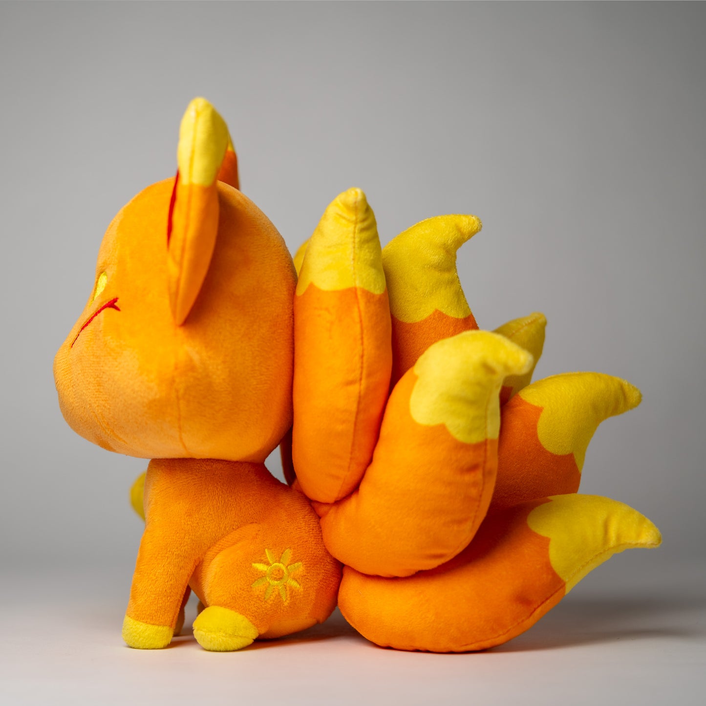 Three-quarter view of Cyrus, a orange, yellow, gold kitsune plush.