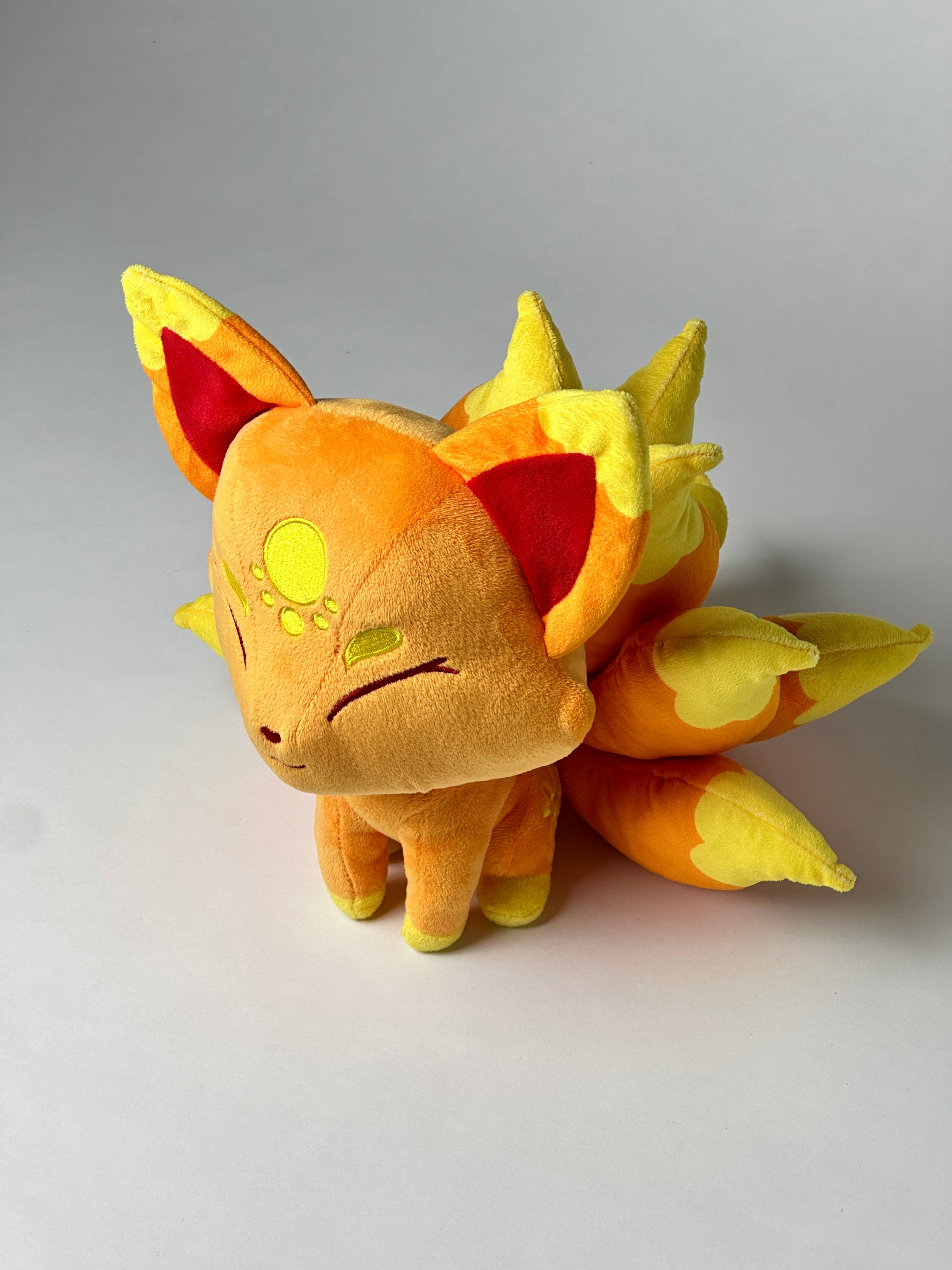 Top view of Cyrus, a orange, yellow, gold kitsune plush.
