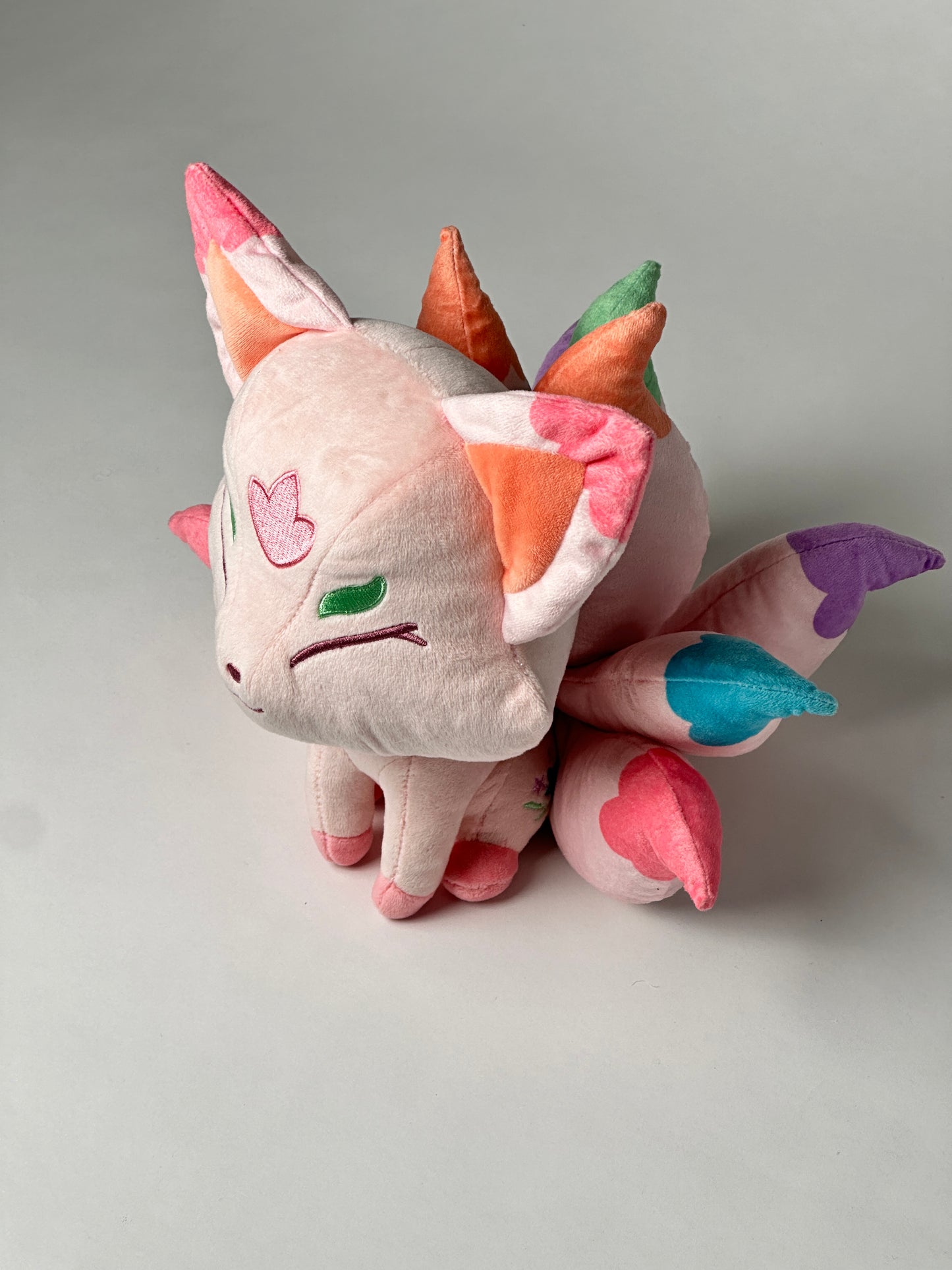 Top view of Flora, a pink, white, turquoise kitsune plush.
