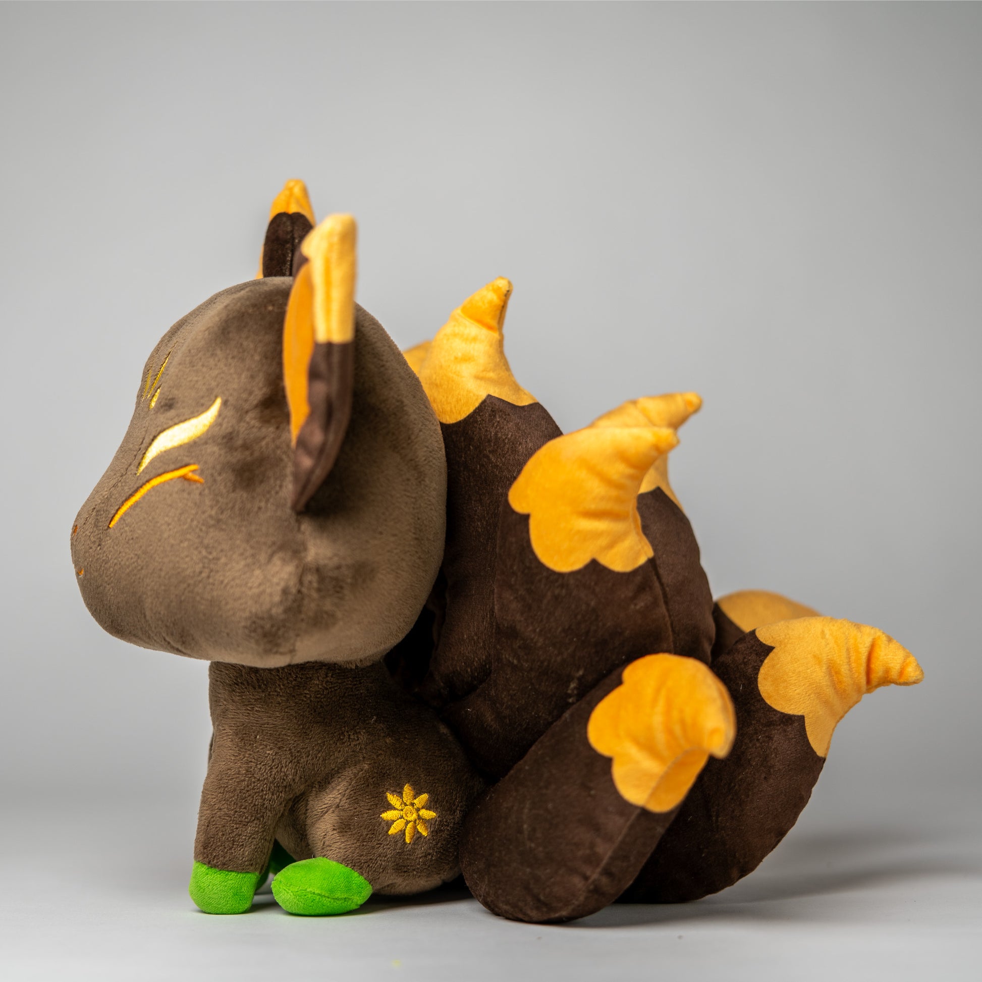 Three-quarter view of Hina, a brown, gold, green kitsune plush.