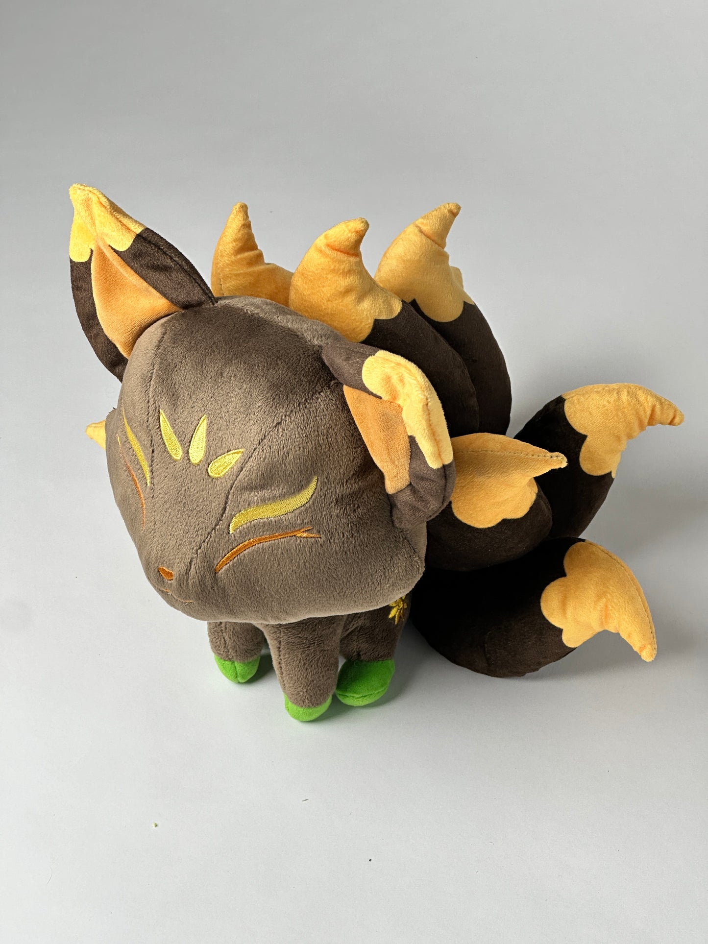 Top view of Hina, a brown, gold, green kitsune plush.