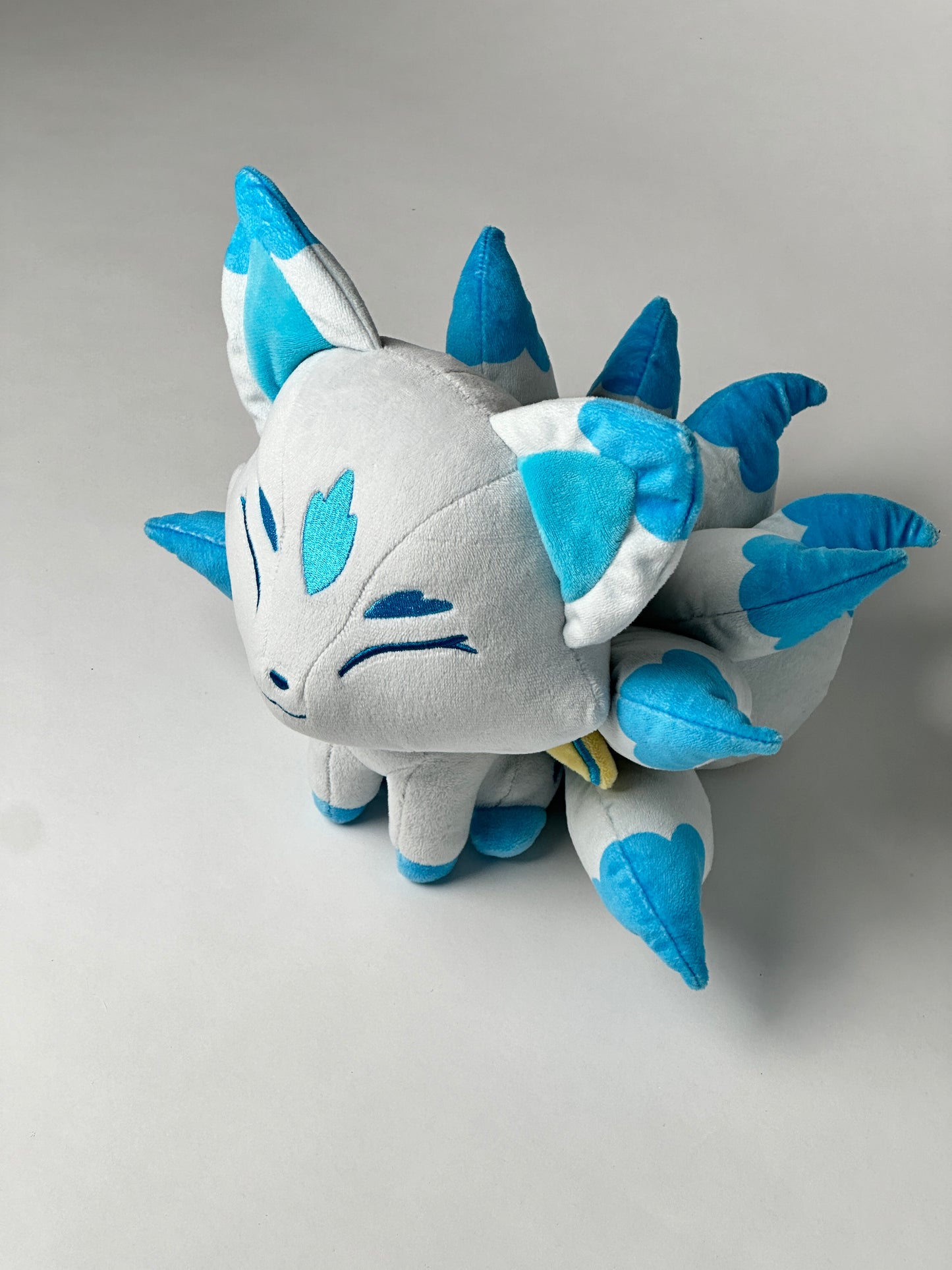 Top view of Icarus, a white, blue, turquoise kitsune plush.