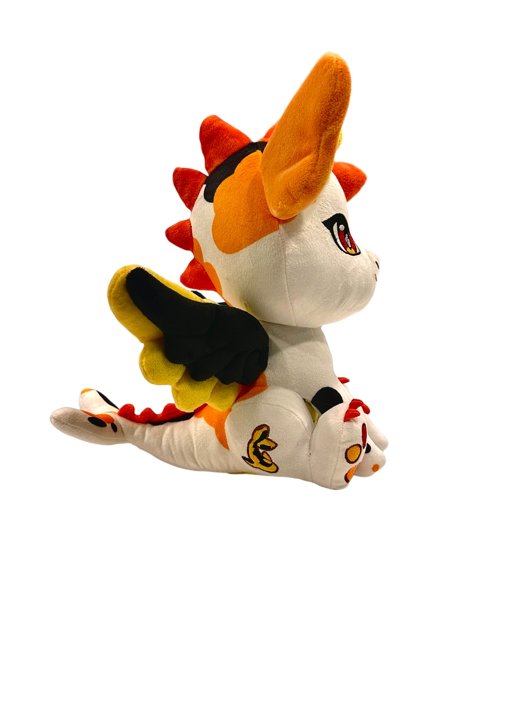 Three-quarter cutout view of Kai, a white, black, orange dragon plush.