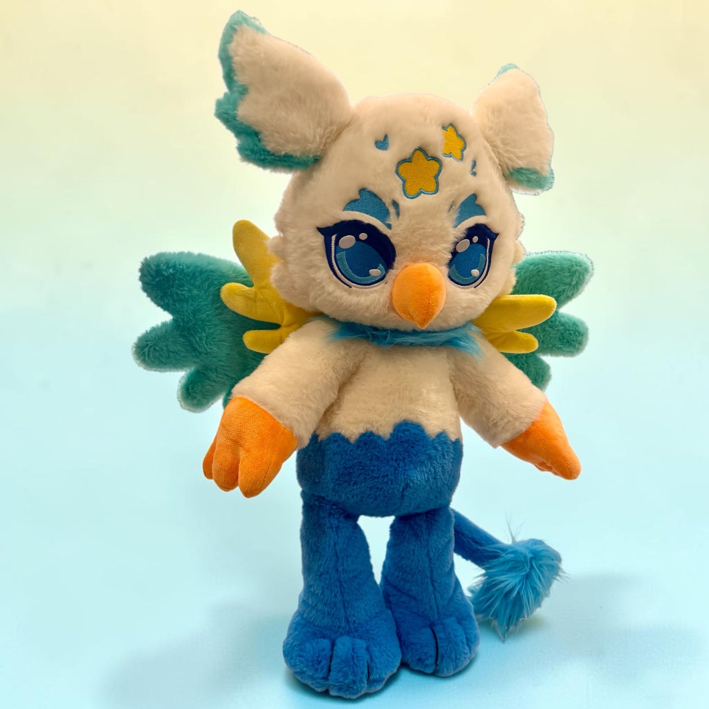 Front standing view of Luca the Griffin, a cream, blue, gold griffin plush.