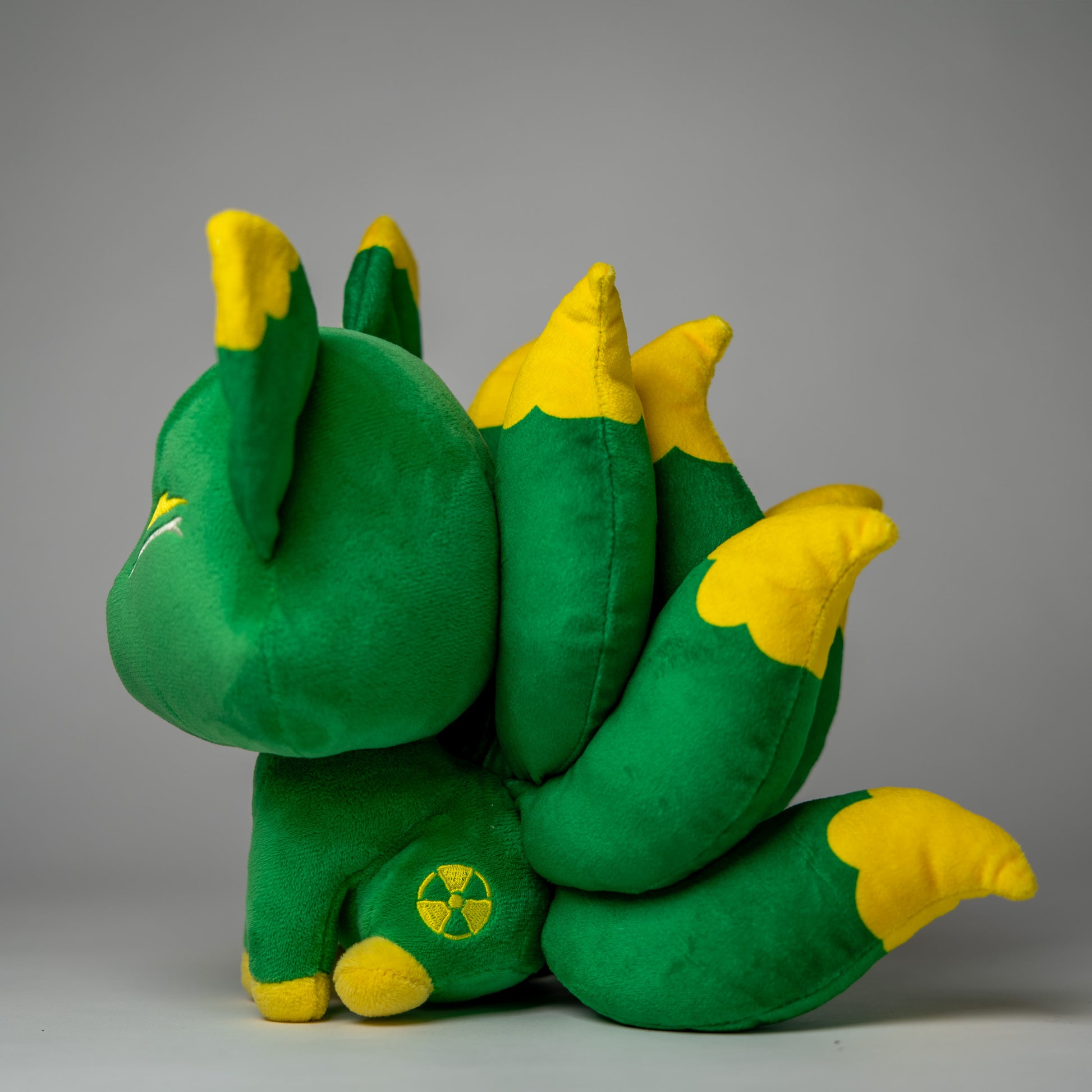 Three-quarter view of Radio, a green, yellow, tan kitsune plush.