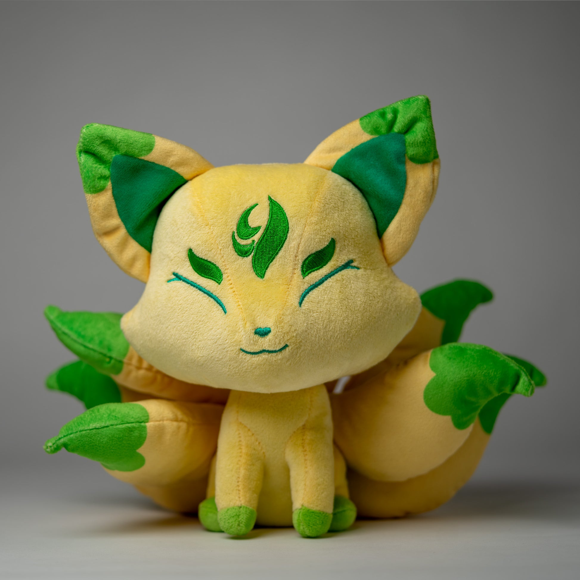 Front view of Silva, a tan, green, yellow kitsune plush.