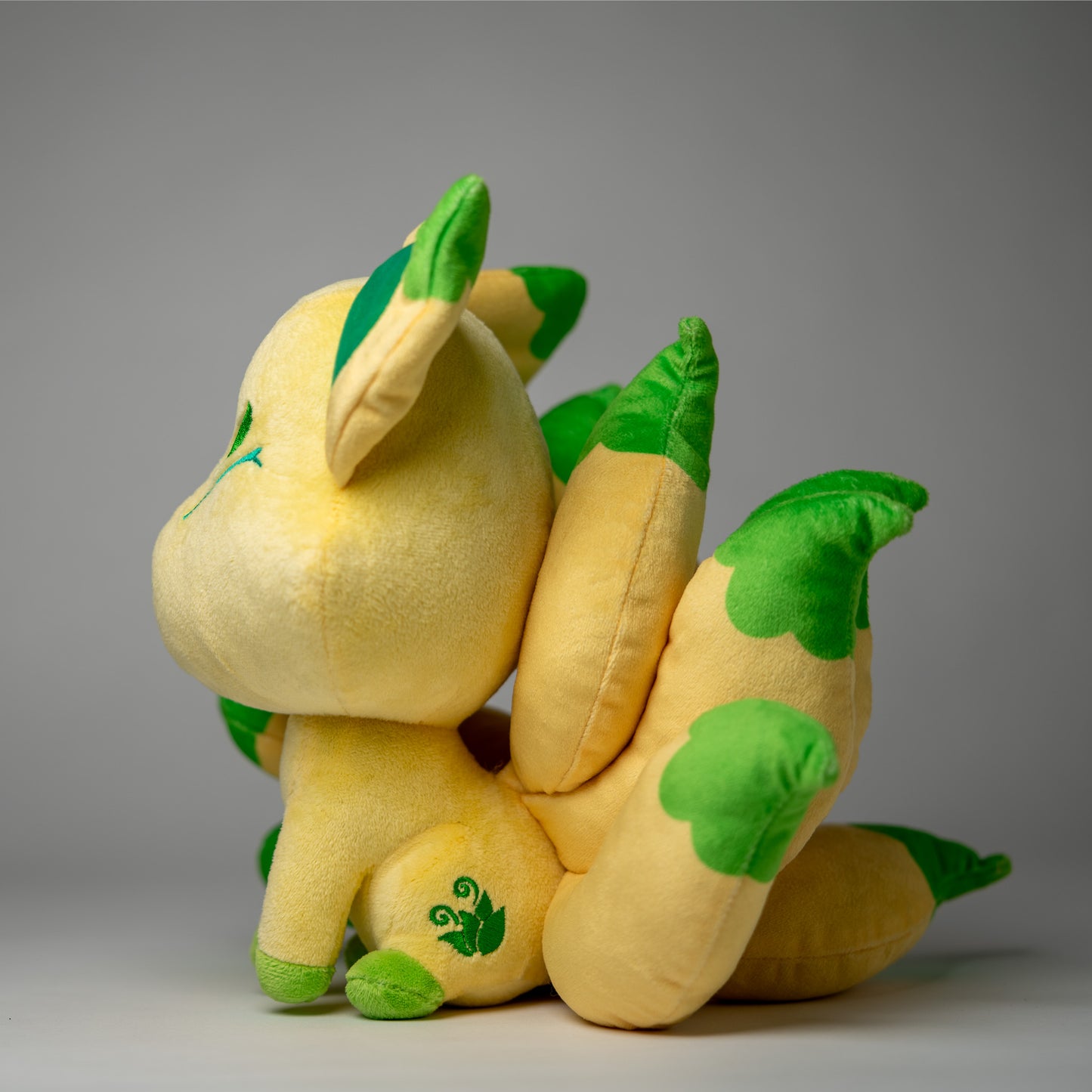 Three-quarter view of Silva, a tan, green, yellow kitsune plush.