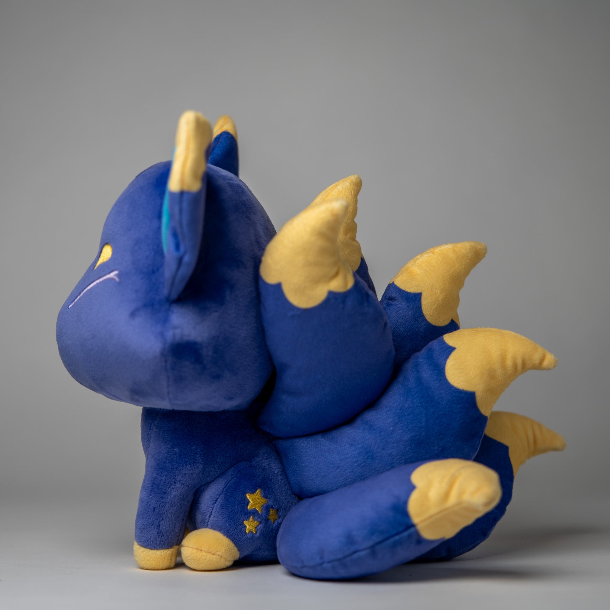 Three-quarter view of Tsuki, a blue, navy, gold kitsune plush.