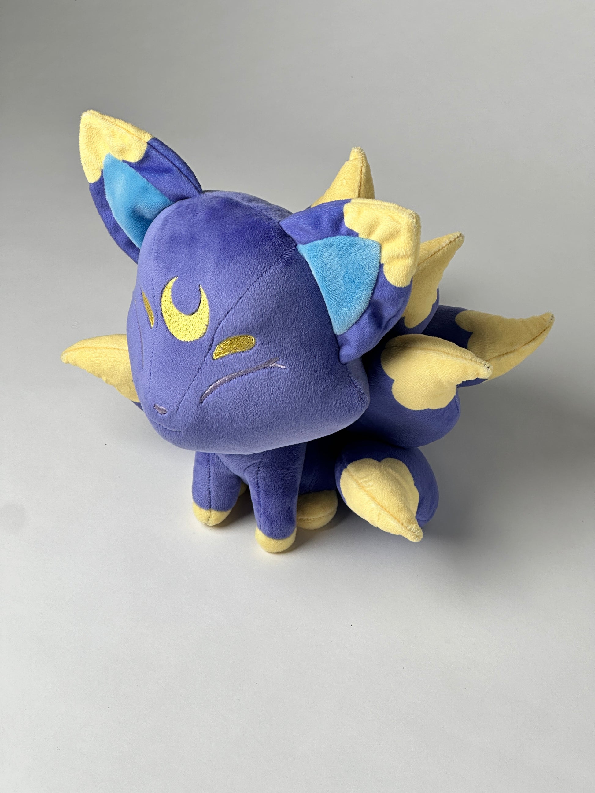 Top view of Tsuki, a blue, navy, gold kitsune plush.