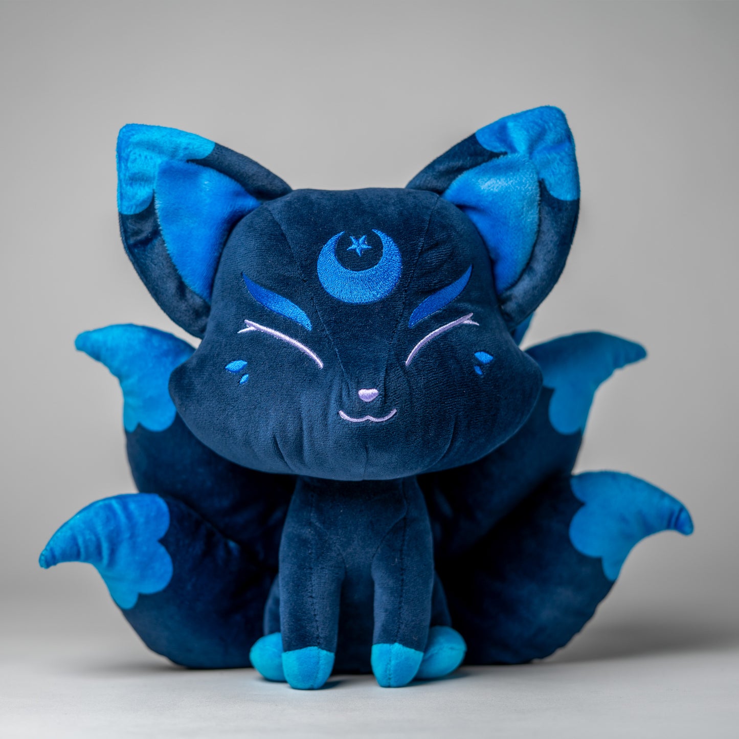 Front view of Zenith, a navy, blue, turquoise kitsune plush.