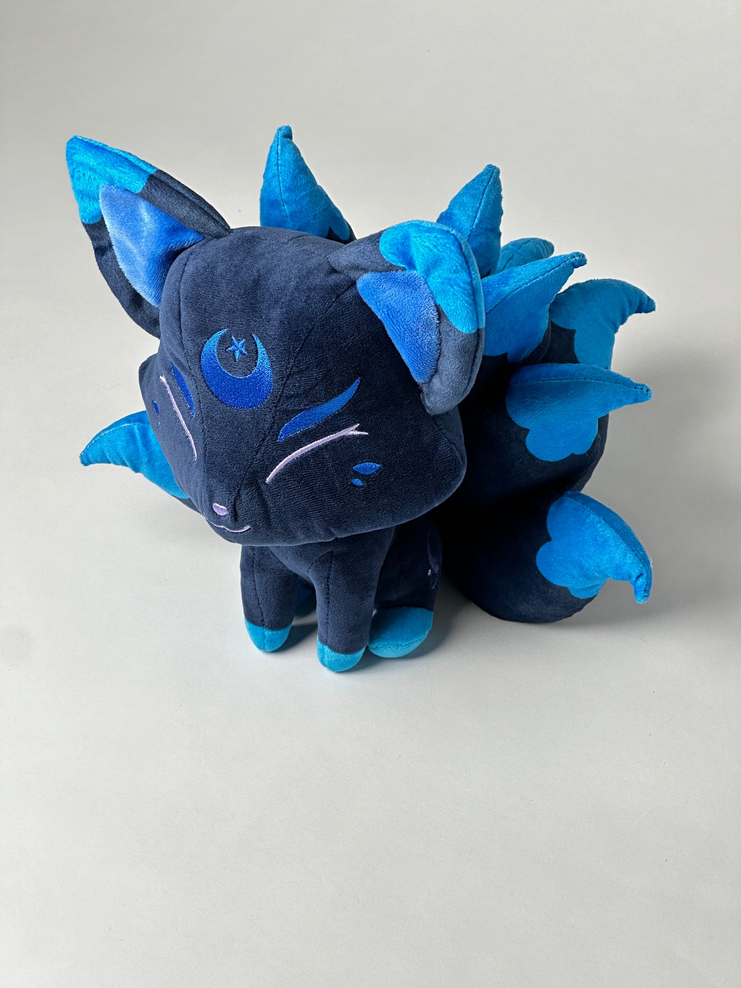 Top view of Zenith, a navy, blue, turquoise kitsune plush.